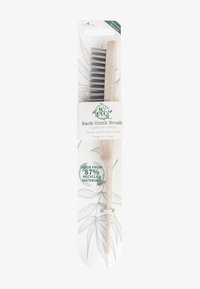Spazzola per capelli con manico in plastica riciclata beige e setole nere, dotata di un'etichetta sulla confezione che sottolinea l'uso di materiali ecologici.