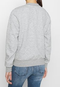 Grijze pullover met een gestructureerd patroon, geribde kraag, manchetten en zoom. Gedragen over een spijkerbroek, met een comfortabele pasvorm.