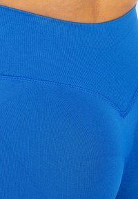 Leggings taille haute bleus avec une texture côtelée et un design sans coutures, dotés de coutures incurvées pour une silhouette ajustée.