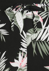 Tissu noir avec un motif de feuilles tropicales blanches et vertes, orné d'un accent floral rose et d'une ceinture assortie à la taille.