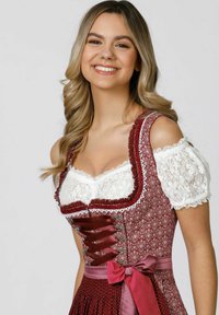 Burgundy dirndl dress with contrasting white lace puff sleeves, decorative lacing, and a waistband bow. Features floral patterns and textured fabric.