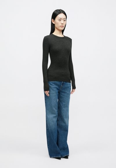 Top ajustado cinza escuro de mangas compridas com textura canelada, combinado com jeans azuis largos de corte clássico reto e bainha crua.