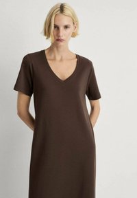 Abito a T-shirt marrone con scollo a V realizzato in tessuto morbido, con maniche corte e vestibilità comoda. Design minimalista senza motivi o dettagli.