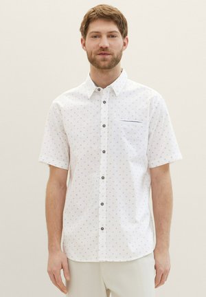 Chemise blanche à manches courtes avec un motif géométrique subtil, dotée d'une poche poitrine et de boutons foncés pour le contraste.