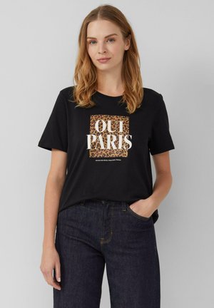 T-shirt en coton noir avec "OUI PARIS" en blanc et des détails en imprimé léopard. Manches courtes, coupe décontractée, associé à un jean en denim foncé.