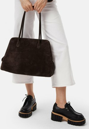 Bruine suède tote tas met twee handvatten, grote rechthoekige vorm en ritssluiting. Gecombineerd met zwarte leren plateau schoenen met dikke zolen.