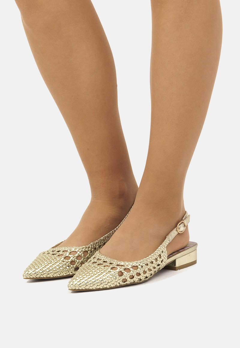 Chaussures slingback dorées tissées avec des bouts pointus, un petit talon plat et une petite boucle décorative, affichant un design ouvert et une surface texturée.