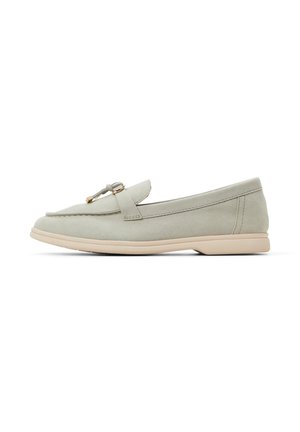 Mocassini in suede grigio chiaro con suola piatta, caratterizzati da un accento con fibbia dorata e dettagli cuciti lungo i bordi.