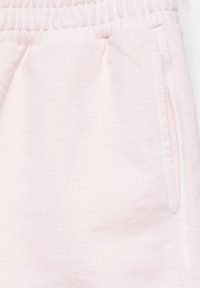 Pantalon de jogging rose clair avec taille élastique et poches latérales, en tissu tricoté doux.