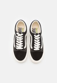 Svarta mockaskor med vita snören och sidorenser. Förstärkt innersula och gummisula. Har kontrasterande sömmar och klassisk design.