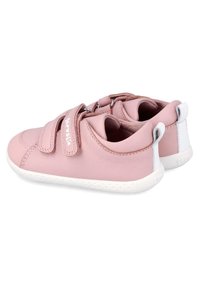 Zapatos de cuero rosa con un acabado suave, que cuentan con dos correas de velcro y suelas de goma blanca. En la parte trasera tienen una pequeña lengüeta y acentos texturizados.