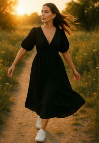 Abito nero, lungo fino al ginocchio, con maniche a sbuffo e scollatura a V profonda. Indossato con sneakers bianche, su uno sfondo di un sentiero erboso soleggiato.