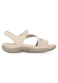 Sandalia beige con tiras elásticas entrelazadas, una plantilla acolchada y una suela de goma flexible con un patrón de agarre texturizado.