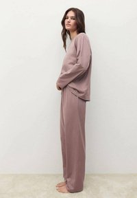Ensemble de loungewear mauve clair comprenant un haut ample à manches longues et un pantalon large, fabriqué dans un tissu doux avec une texture lisse.