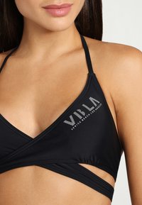 Schwarzer Bikini-Oberteil mit einem dreieckigen Design, das überkreuzte Träger und den Schriftzug "VILA VENICE BEACH LOS ANGELES" in silberner Schrift enthält.