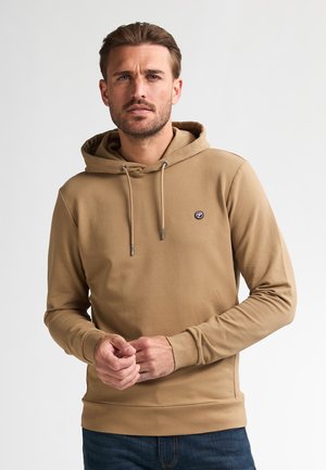 Beige Kapuzenpullover mit einer Fronttasche und Kordelzug. Verfügt über ein kleines Logo auf der Brust. Lange Ärmel und enganliegende Bündchen.