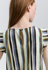 Top in tessuto testurizzato con righe verticali multicolori in blu, verde, nero e beige. Presenta un'apertura a chiave sul retro e maniche corte.