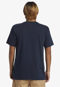 Marinblå bomulls t-shirt med korta ärmar, rundad halsringning och avslappnad passform. Tyget verkar mjukt med en enkel design och inga synliga mönster.