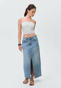 Hvid og blå stribet cropped top parret med en lys blå denim maxi nederdel med en slid foran. Bæres med flade sandaler.