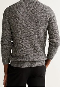 Maglione grigio lavorato a maglia con un motivo testurizzato, maniche lunghe, polsini e orlo a coste. La vista posteriore mostra un design aderente e tonalità di colore neutre.