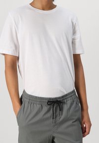 Vit bomullströja med rundad halsringning och korta ärmar, i kombination med grå shorts med dragsko som har elastisk midja och sidofickor.