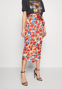 Gonna midi floreale con fiori arancioni e rossi su uno sfondo crema. Il tessuto appare liscio; presenta una vita legata e uno spacco laterale.