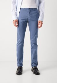 Chinos bleu clair en tissu tissé, présentant une coupe slim, des poches latérales et un design à devant plat. Associés à des chaussures en cuir noires.