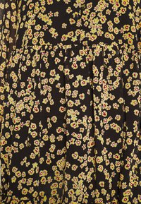 Zwarte stof met een klein, levendig bloemenpatroon in geel en rood. Bevat plooien en heeft een zachte, lichte textuur.