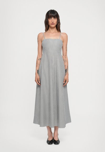Gestreiftes Maxikleid mit dünnen Trägern, versehen mit einem eng anliegenden Oberteil und einem ausgestellten Rock. Farbgestaltung: Weiß und Marineblau. Glatte Stoffstruktur.