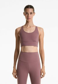 Sportbeha van mauve stof met een ronde hals, brede banden en een naadloos ontwerp. Gecombineerd met bijpassende hoge taille leggings.