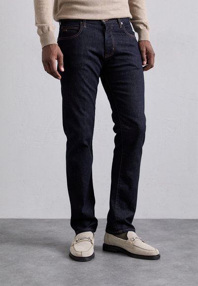 Тъмносини дънки сSlim fit, с контрастни оранжеви шевове, предни джобове и цип. Съчетава се с обувки тип лофери в светъл цвят.