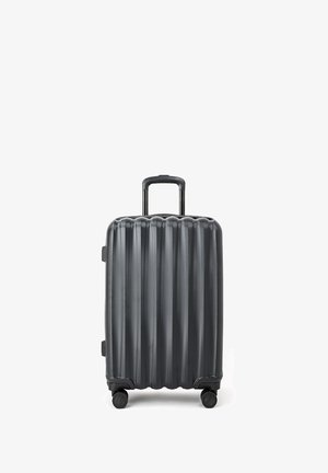 Walizka twarda w ciemnoszarym kolorze z pionowym żebrowanym wzorem, z teleskopową rączką i czterema kółkami zapewniającymi łatwość w poruszaniu się.
