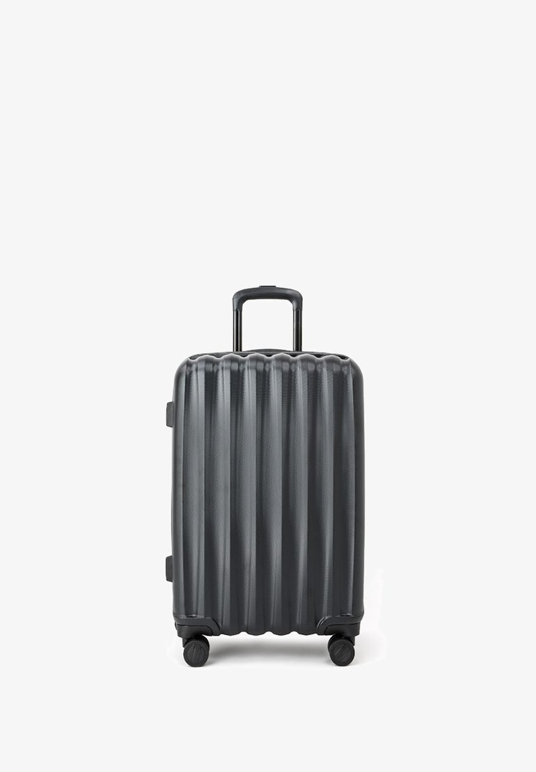 Walizka twarda w ciemnoszarym kolorze z pionowym żebrowanym wzorem, z teleskopową rączką i czterema kółkami zapewniającymi łatwość w poruszaniu się.