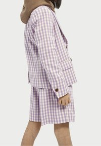 Lila rutigt kostym med blazer och matchande shorts, med en brun huva. Knappar på ärmarna och fickdetaljer är synliga.