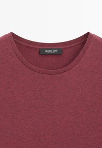 T-shirt bordeaux a maniche corte in cotone morbido, con una superficie testurizzata e un'etichetta con la scritta "Massimo Dutti, Made in Portugal."