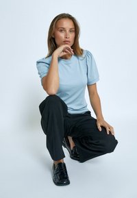 Gaiši zils ribots īsais piedurknes tops apvienots ar melniem platām biksēm un spīdīgiem melniem mokasīniem. Minimālistisks dizains, gluda tekstūra.