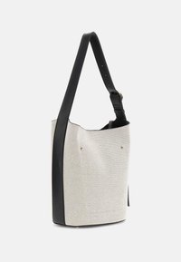 Buckettas met een gestructureerd, lichtgrijs stoffen lichaam en zwarte leren accenten. Beschikt over een enkele zwarte schouderriem en goudkleurige hardware.
