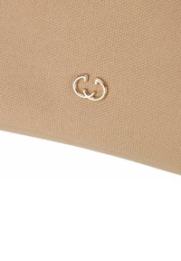 Sac à main en toile beige avec un accent en logo double G doré ; texture lisse avec un léger motif tissé.