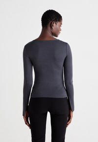 Long-sleeve shirt in dark gray, with a fitted design and a boat neckline, made from smooth fabric. Cut-out details at the sleeve ends.