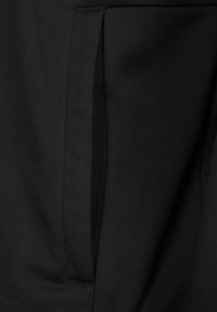 Zwarte stof met een gladde textuur, met een verticale zakdetail dat in het ontwerp is geïntegreerd, wat een minimalistische uitstraling creëert.