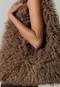 Bruine, fluffy vest met een gestructureerd, bont ontwerp. Kenmerkt zich door een losse pasvorm met een open voorkant en een zachte, warme uitstraling.