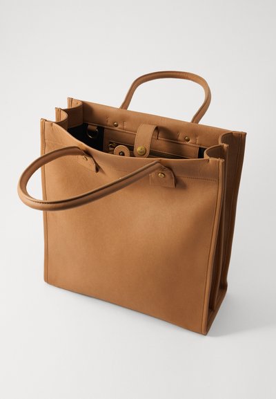 Borsa a mano in pelle marrone con due manici, apertura superiore e tasche interne. Texture liscia, hardware minimo e forma rettangolare.