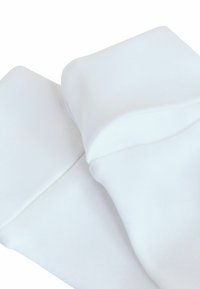 Fehér pamutszárú zoknik sima textúrával, bordás szegéllyel és varrás nélküli lábujjal, laposan elhelyezve enyhe ráncokkal.
