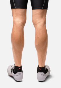 Specialiserede cykelsko i hvid med sorte accenter har et slankt design, perforeret tekstur og en markant spændeåbning.