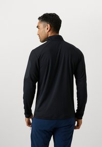 Schwarzer lang�ärmeliger Pullover mit hohem Kragen, ausgestattet mit strukturierten Schulterakzenten und einem taillierten Design, gefertigt aus einem leichten, atmungsaktiven Stoff.