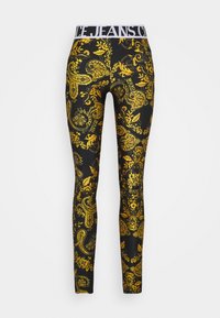 Schwarze Leggings mit einem goldenen, aufwändigen Muster, ausgestattet mit einem weißen elastischen Bund, der mit "JEANS" gekennzeichnet ist. Glatte Textur und enganliegendes Design.