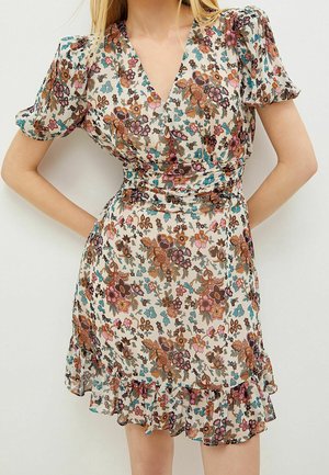 Floral Wickelkleid mit Puffärmeln und gerafftem Saum in Beige-, Braun-, Rosa- und Blautönen an einer Person mit in die Hüften gestützten Händen.