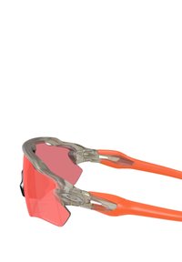 Occhiali da sole sportivi con una montatura grigia trasparente e templi arancioni, dotati di lenti rosa e un design aerodinamico per una visibilità migliorata.
