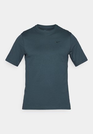 T-shirt à manches courtes en teal foncé en tissu mélangé coton, avec un col rond et un petit logo Nike noir sur la poitrine.