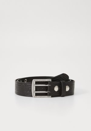 Black rubber belt with an embossed pattern, featuring a silver metal buckle and prong, and adjustable holes for sizing.